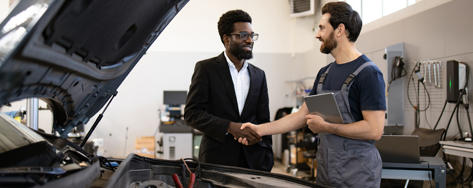 Two men shaking hands in a repair garage