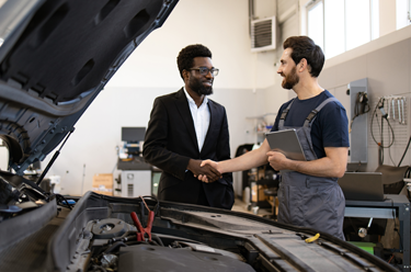 Two men shaking hands in a repair garage