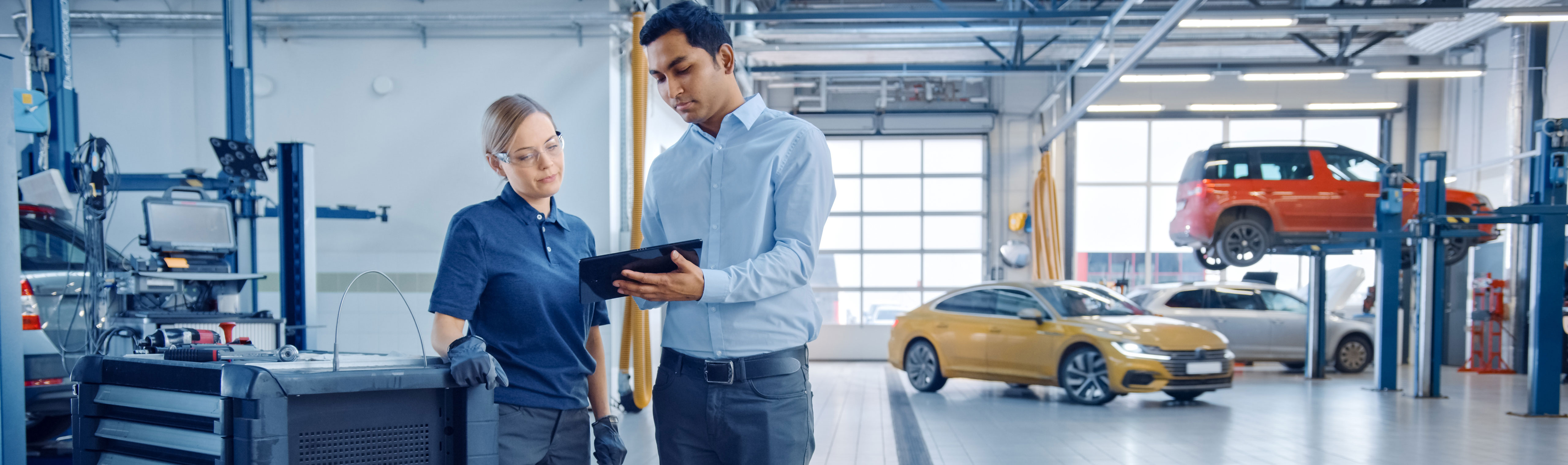 Two people in a garage looking at maintenance schedules