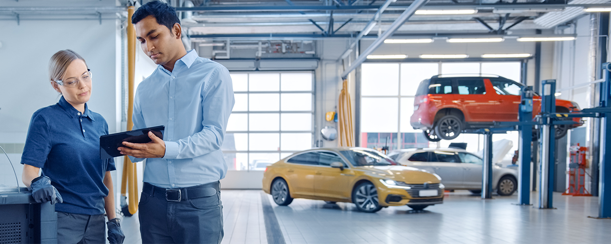 Two people in a garage looking at maintenance schedules