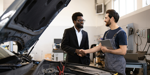 Two men shaking hands in a repair garage