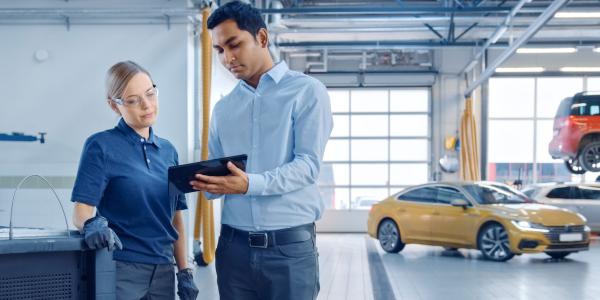 Two people in a garage looking at maintenance schedules