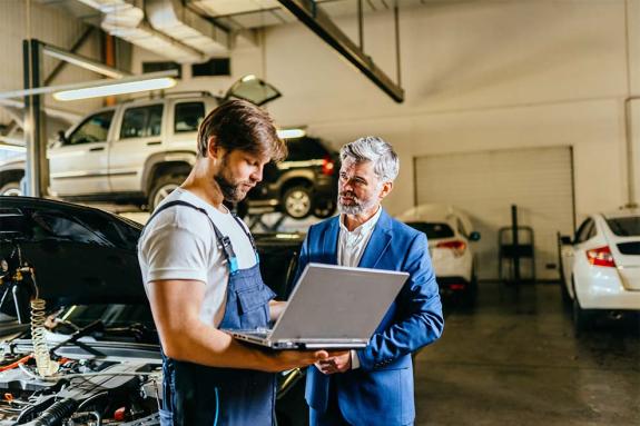 Two men chatting in a workshop with a laptop