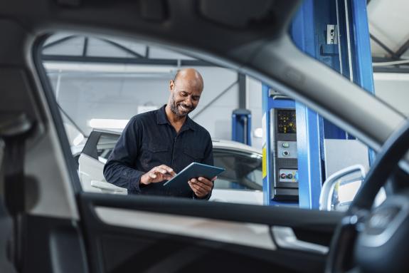 Ein männlicher Mechaniker mit Tablet am Autofenster 