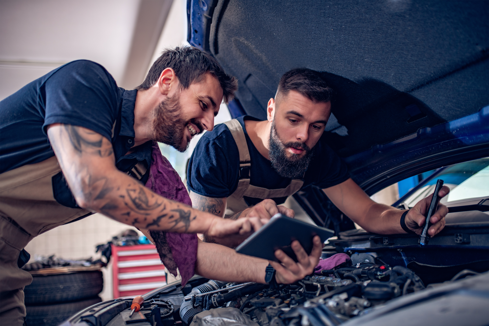two men looking over an engine with one of them pointing to a screen