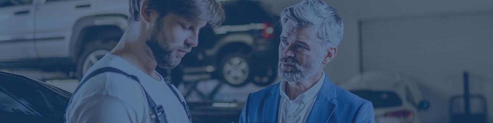 Two men chatting in a workshop with a laptop